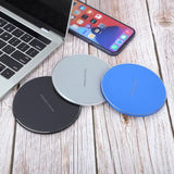 Cargador inalámbrico rápido de color azul, negro, gris al lado de laptop y iPhone
